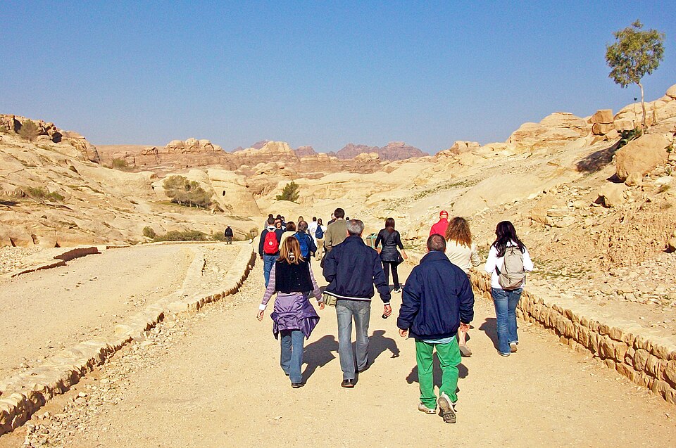 Visitors walking along the sandy road to the Siq at Petra